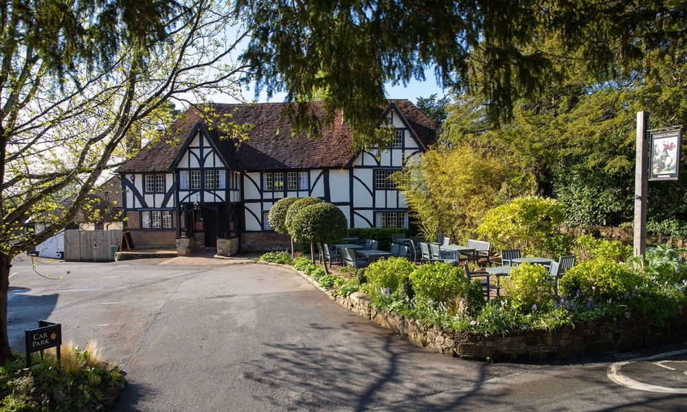 The handsome exterior of the tudor-style pub, The George & Dragon in Speldhurst surrounded by greenery