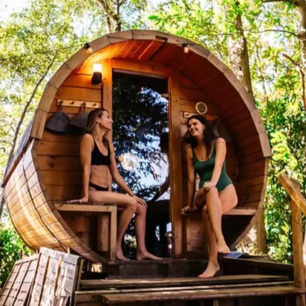 the-hotbox-sauna two people sitting outside a sauna in the forest