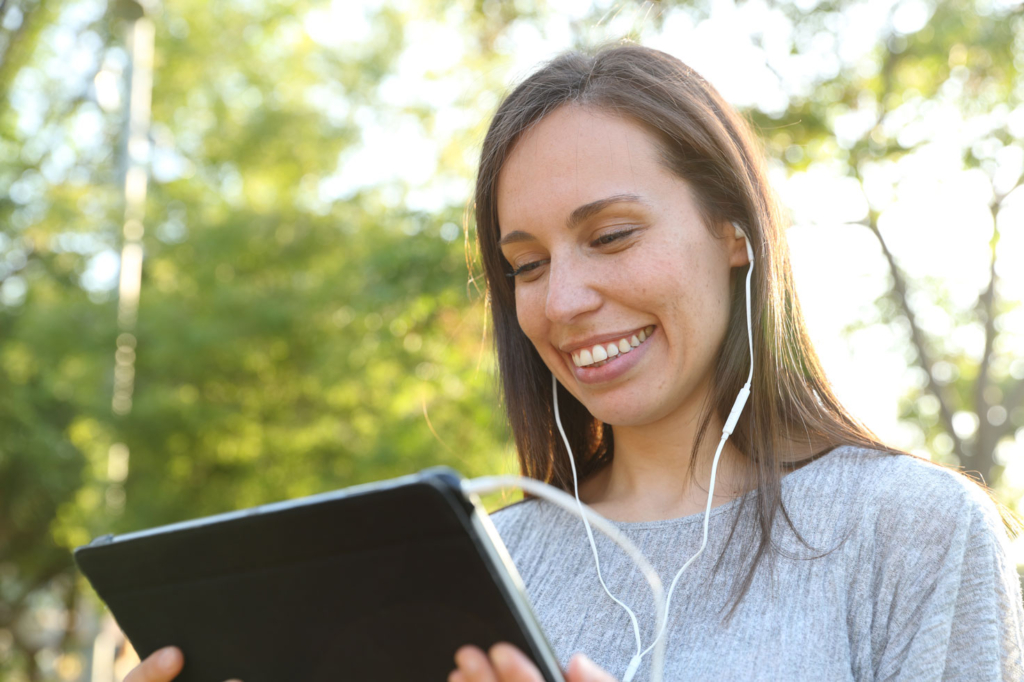 Woman with earphones listening to the audio trail on her tablet