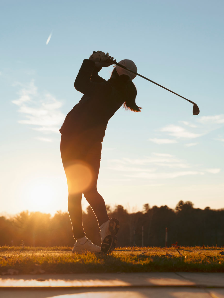 Lady playing golf at sunset