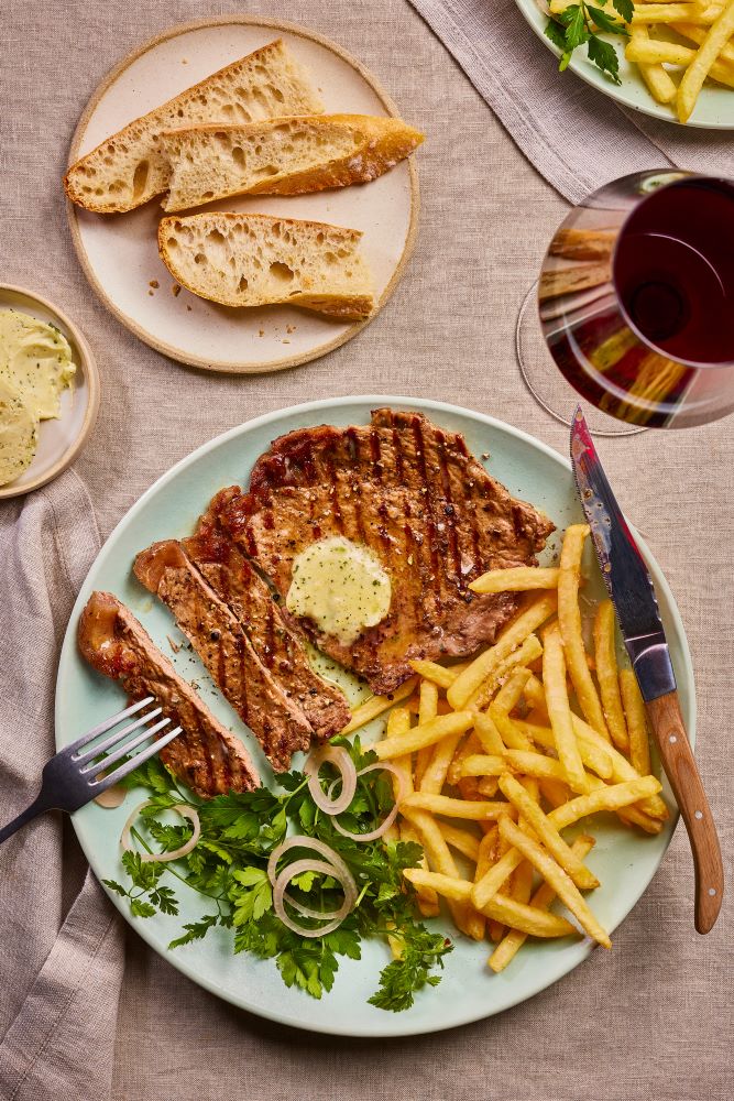 A Steak with fries, veg and bread.