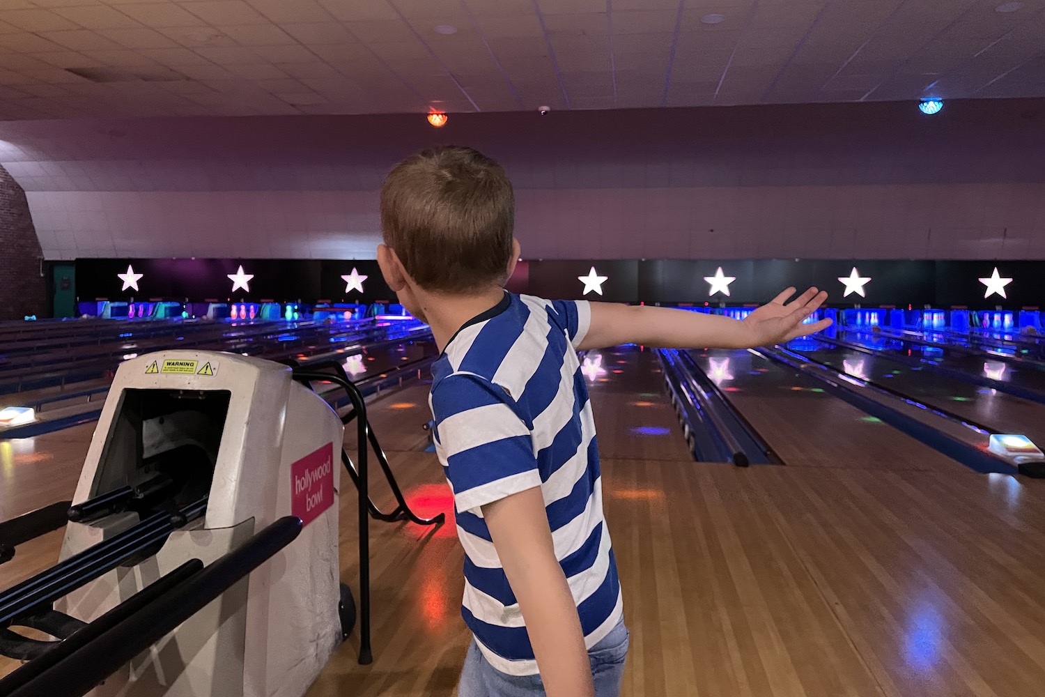 a young boy bowling a ball in a bowling alley