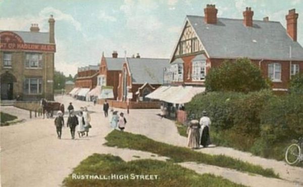 A historical image of Rusthall High Street showing numerous buildings and people