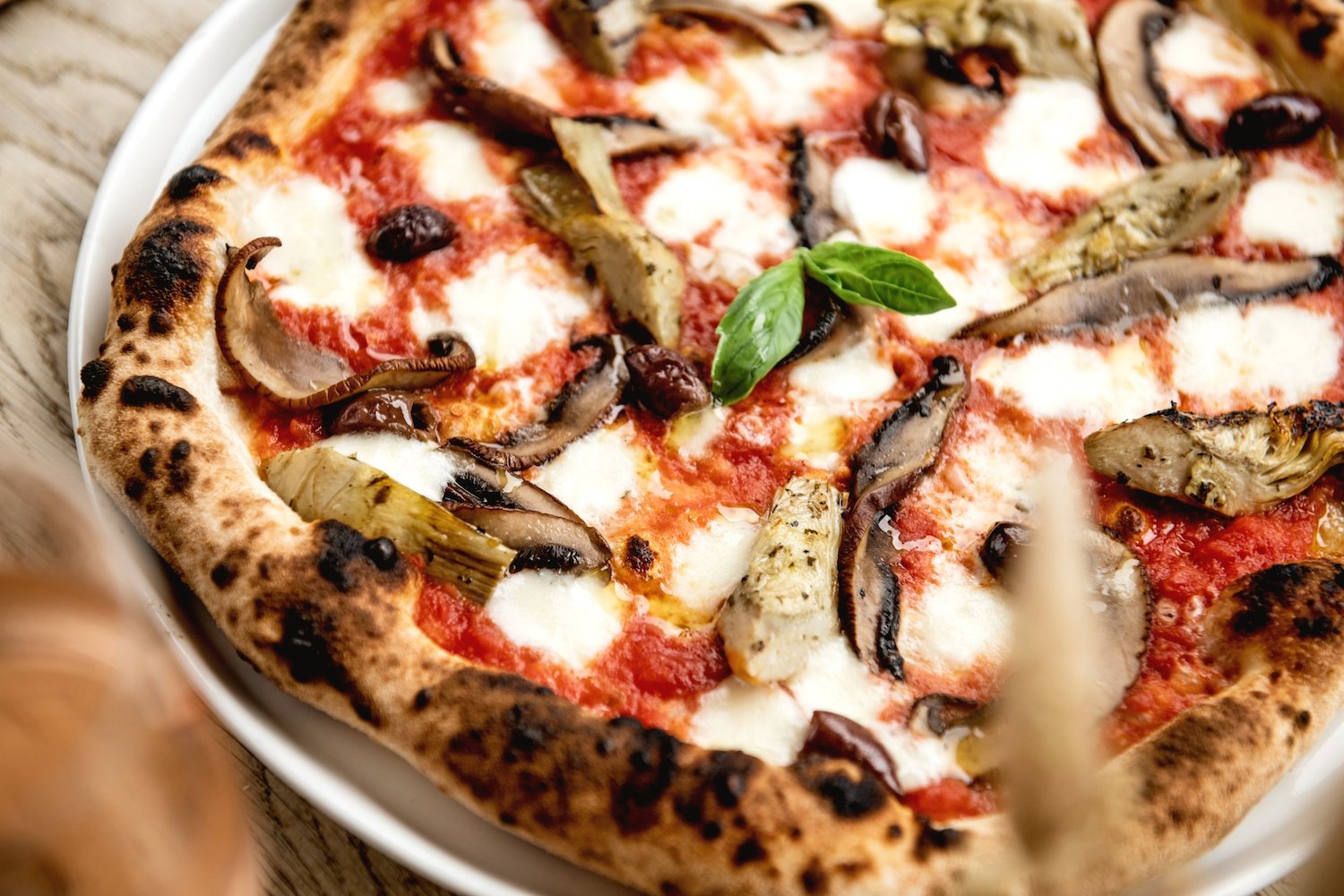 A close-up picture of an Italian wood-fired pizza filled with toppings