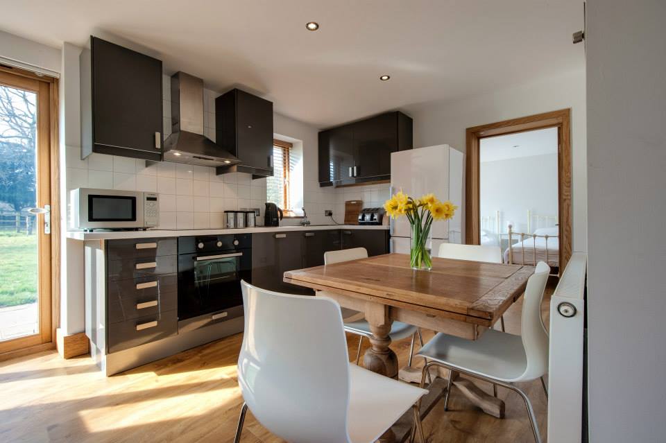 An interior shot of a small kitchen with a dining table and two chairs with a door leading into a bedroom in the background