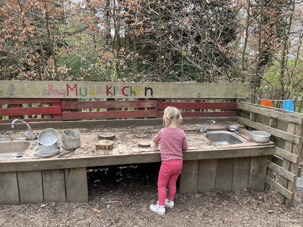 A young child playing with a mud kitchen outside