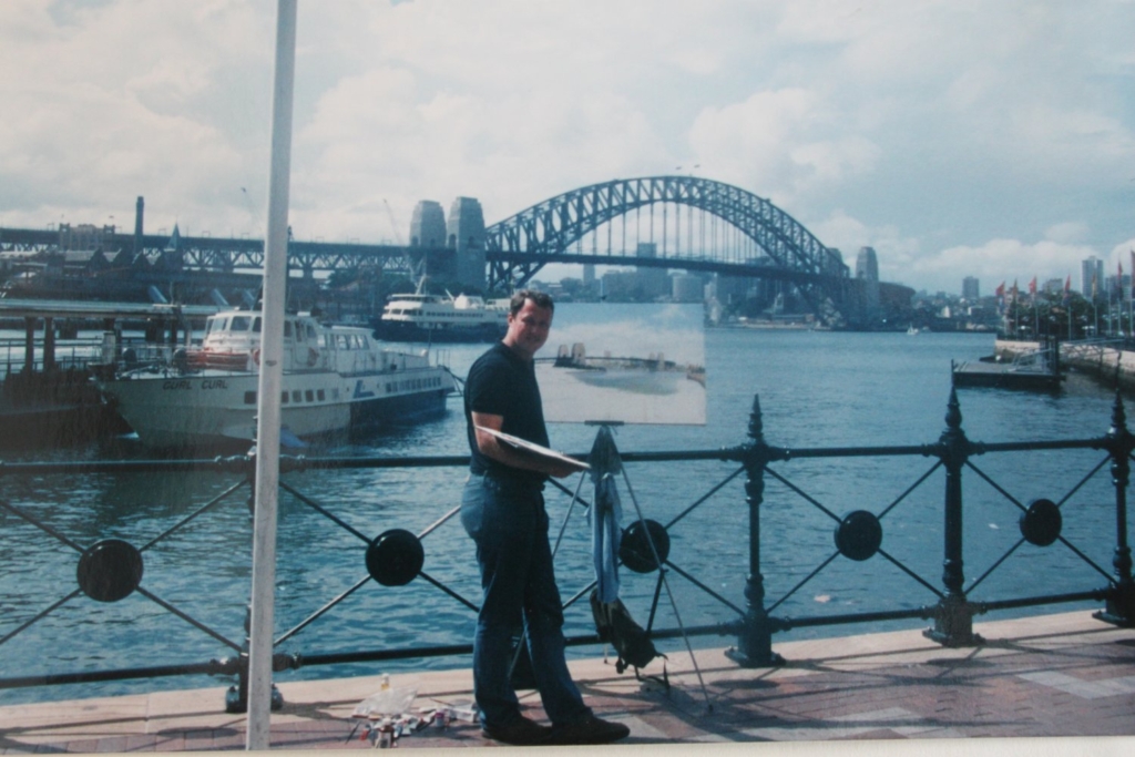 a man standing in front of the Sydney bridge. Graeme Lothian is painting