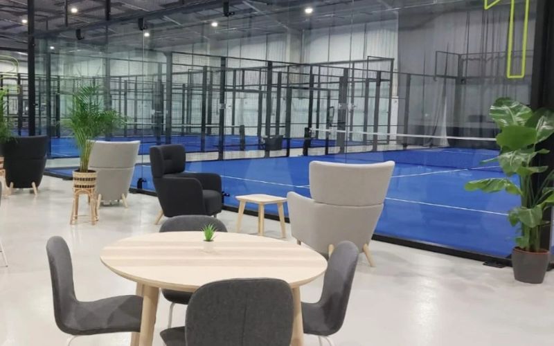 padelhub 800×500 Interior of indoor Padel center with cafe seating in foreground